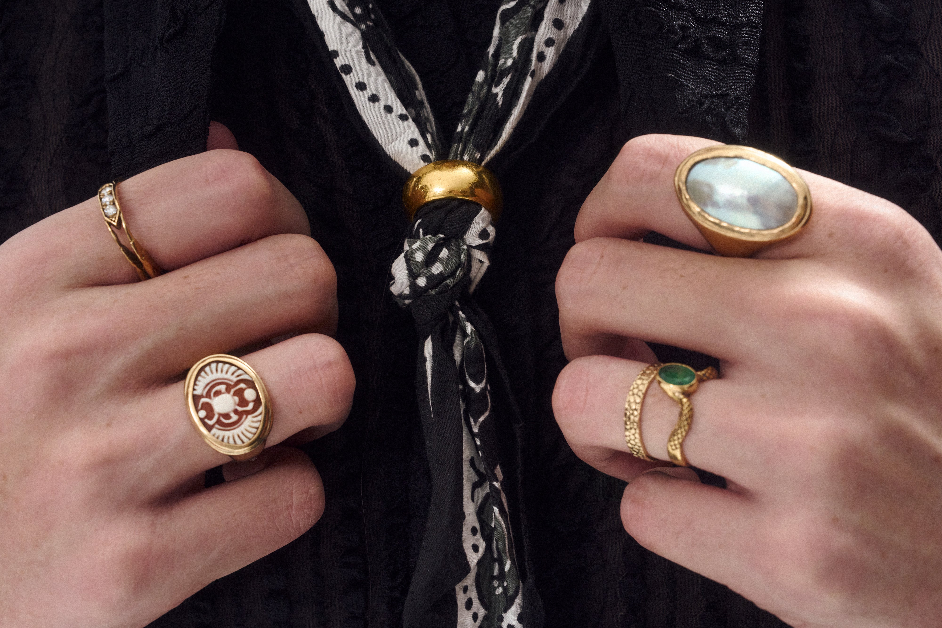 A photograph of two hands holding a black shirt wearing gold rings.