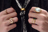 A photograph of two hands holding a black shirt wearing gold rings.