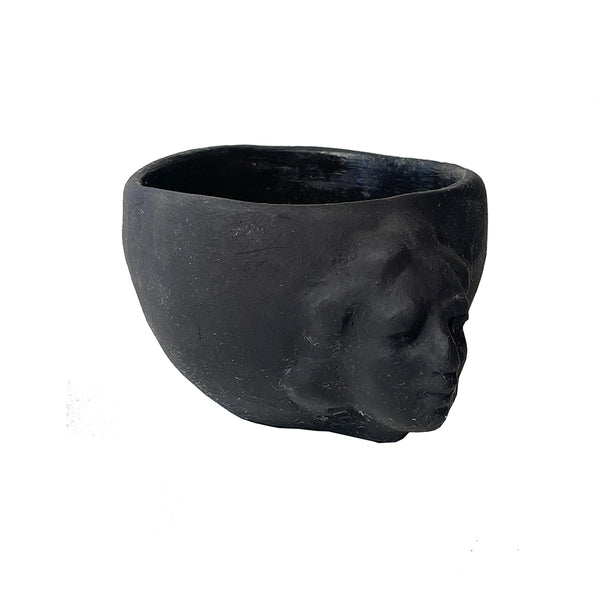 Black ceramic planter shaped like a face on a white background