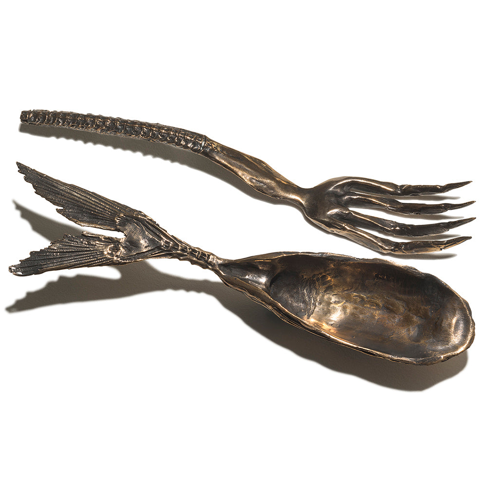 Silver spoon and fork with fish tail design on a white background
