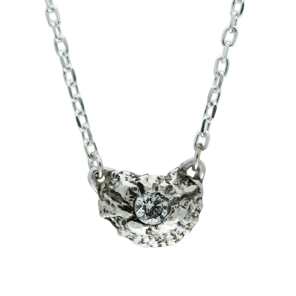 silver barnacle pendant set with white diamond on a white background