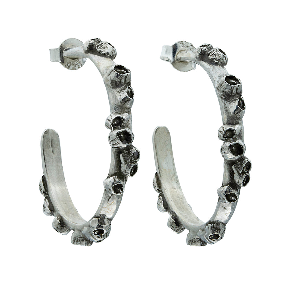 Pair of silver barnacle encrusted hoop earrings with black accents on a white background