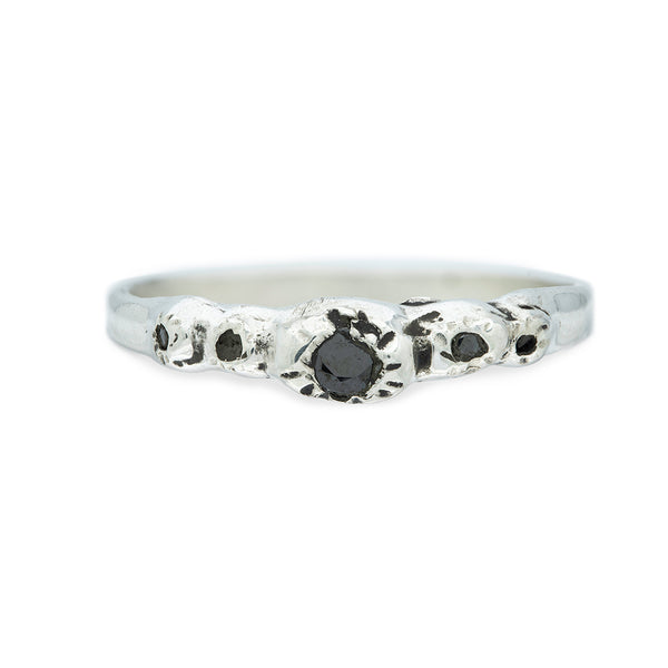 silver ring with barnacle details holding black diamonds on white background
