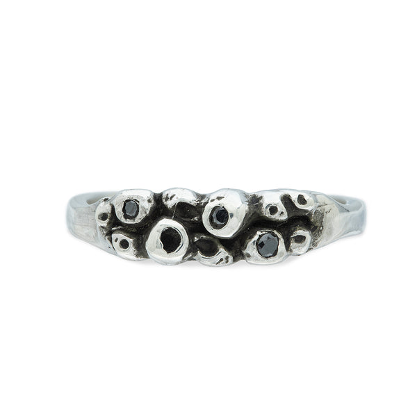a ring with a cluster of silver barnacles set with black diamonds on a white background 