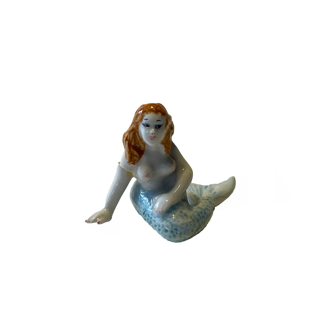 Mermaid figurine with a white body and blue tail on a white background
