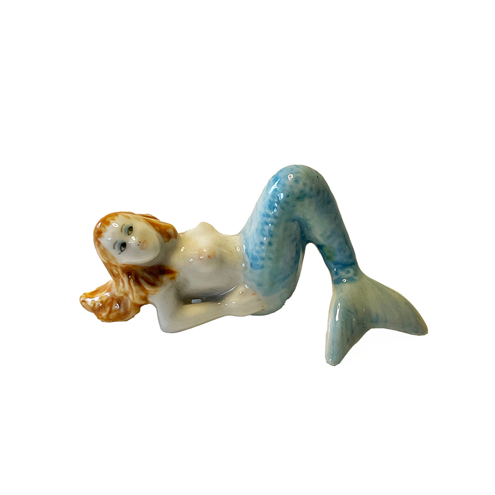 Small ceramic mermaid figurine with a blue tail on a white background
