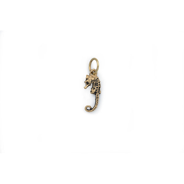 A small gold seahorse facing left hanging from a round gold jump ring.