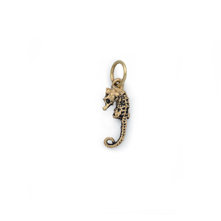 A small gold seahorse facing left hanging from a round gold jump ring.