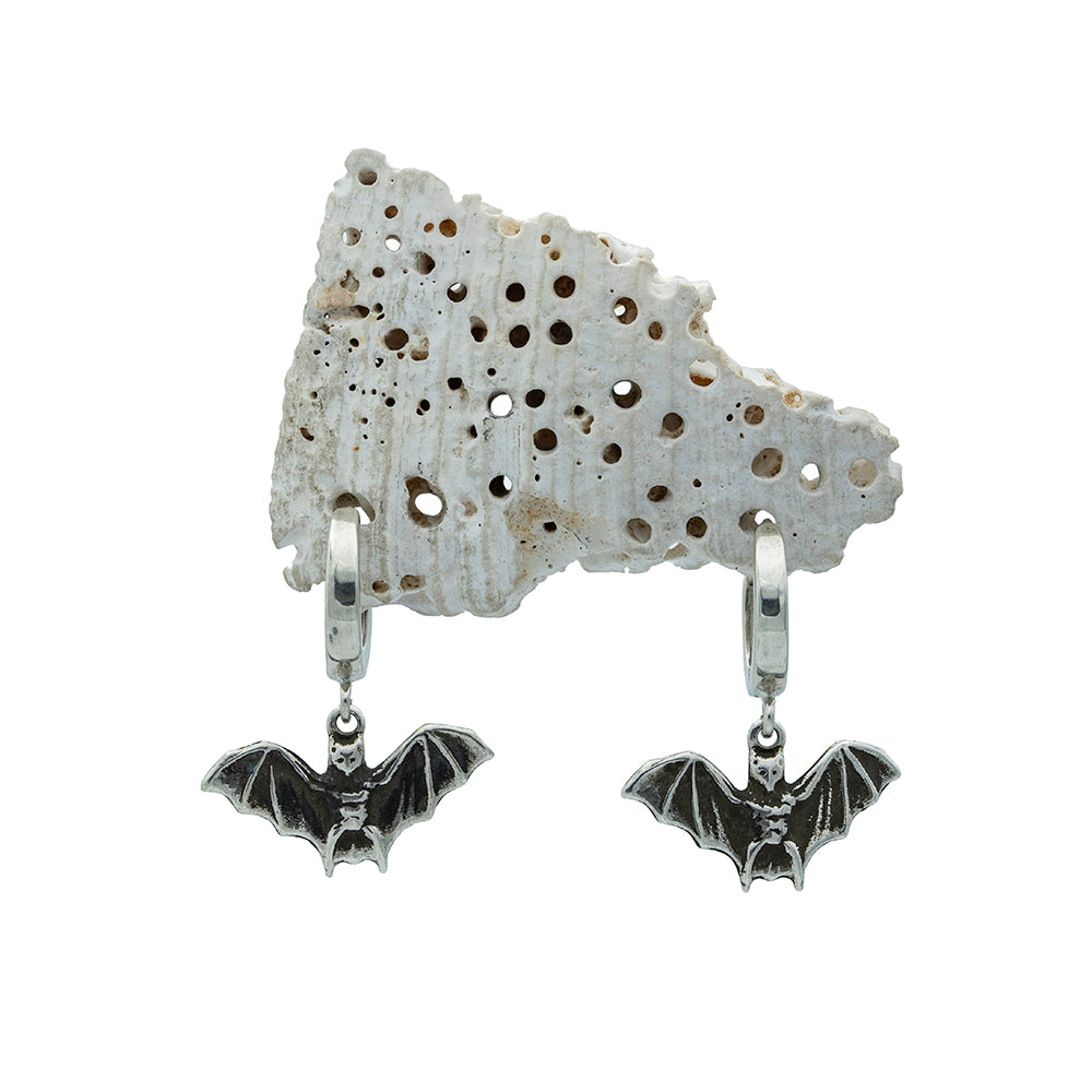 Bat-shaped earrings on a textured stone background