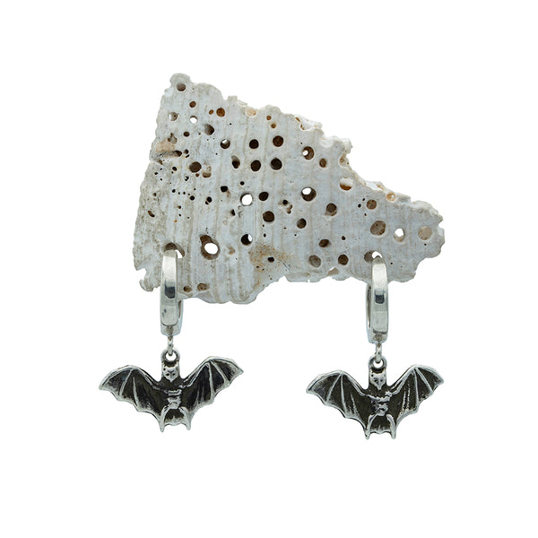 Bat-shaped earrings on a textured stone background