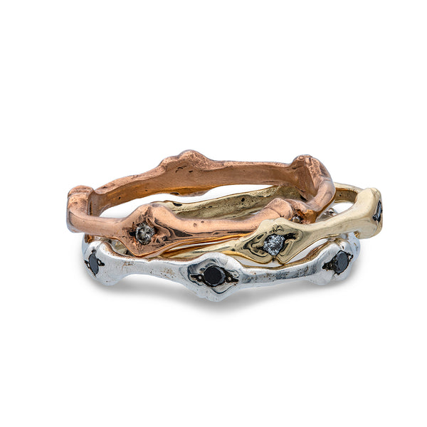 a stack of three band rings in silver, yellow and rose gold set with diamonds