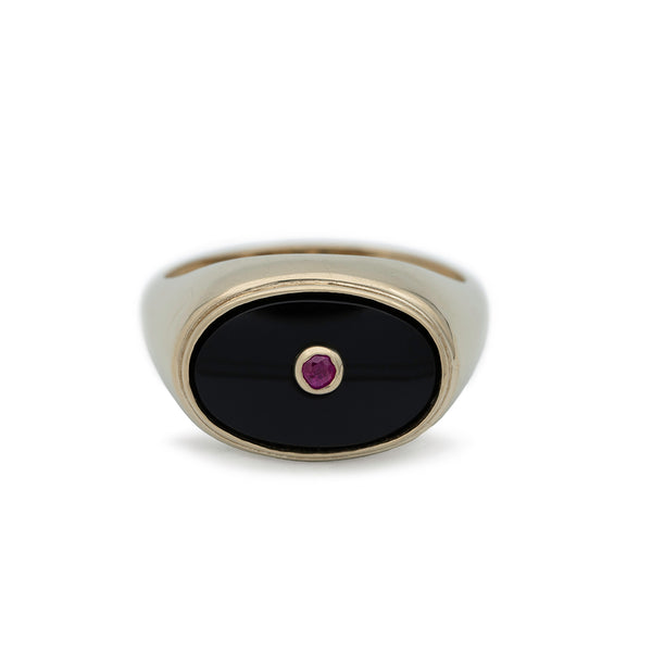 A gold ring set  with an oval black onyx.  Inside the black onyx is a small round ruby set in gold.