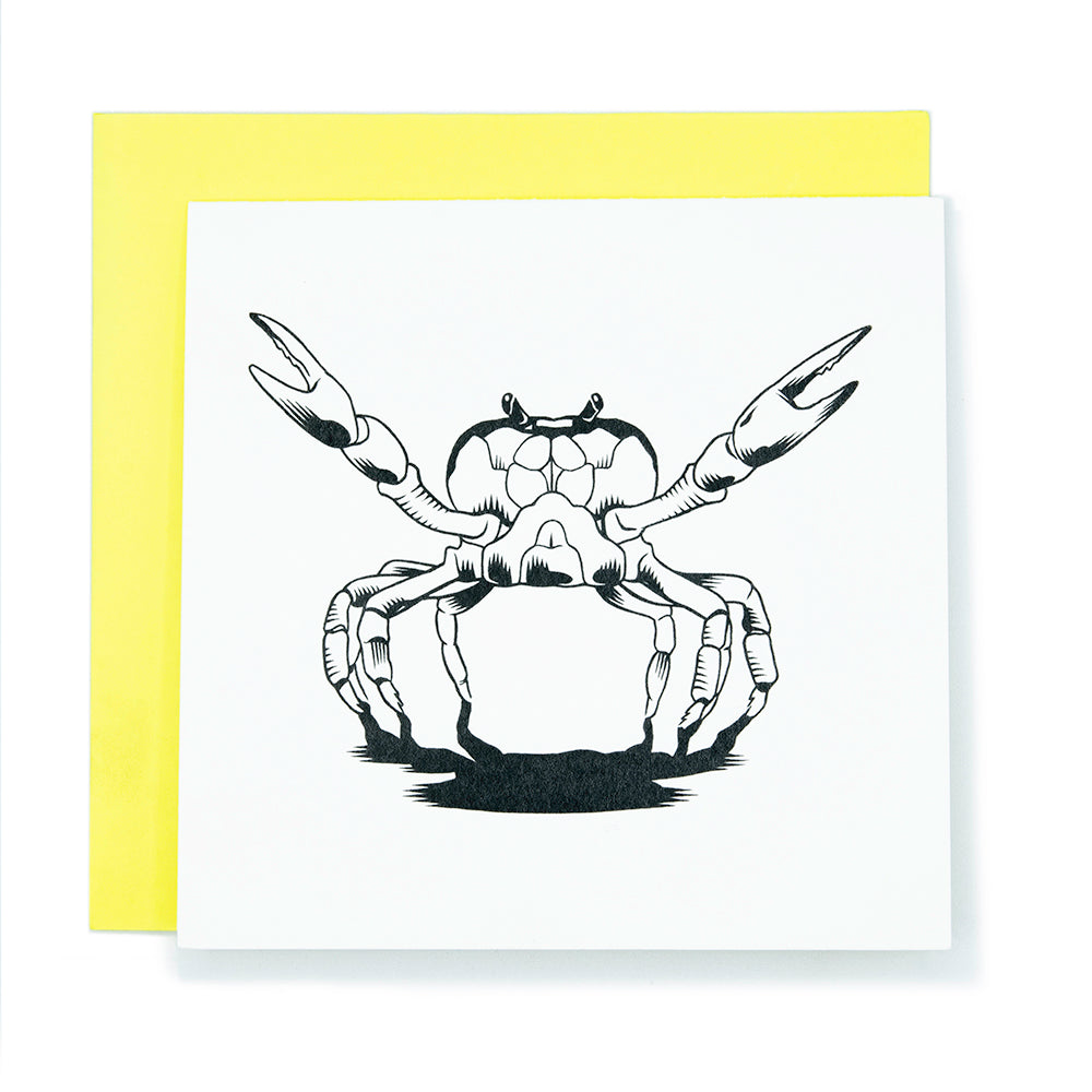 A square greeting card with a black and white illustration of a crab with its claws raised like open arms.  It sits on a bright yellow envelope background.