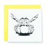 A square greeting card with a black and white illustration of a crab with its claws raised like open arms.  It sits on a bright yellow envelope background.