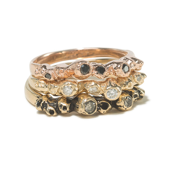 A stack of three gold rings with barnacle details  set with diamonds.