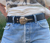 A model shot of a black belt with a bronze horseshoe crab buckle