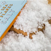 Close-up of sea salt flakes with a box labeled 'Coarse Sea Salt' in the background.