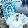 blue nordur salt tin with salt in shell in front of water background