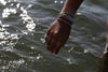 A model shot of  tan arm with silver bracelets and rings.  The arm is over ocean water.