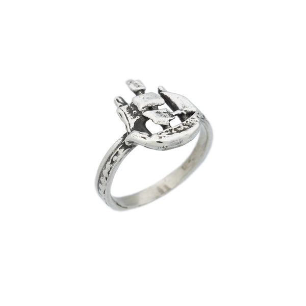 Side view of a  silver ring featuring a sculpted sailing ship atop the band.