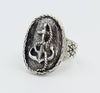 Sideview of a silver ring with an anchor detail with rope winding through and engraving of a ships wheel on the side.
