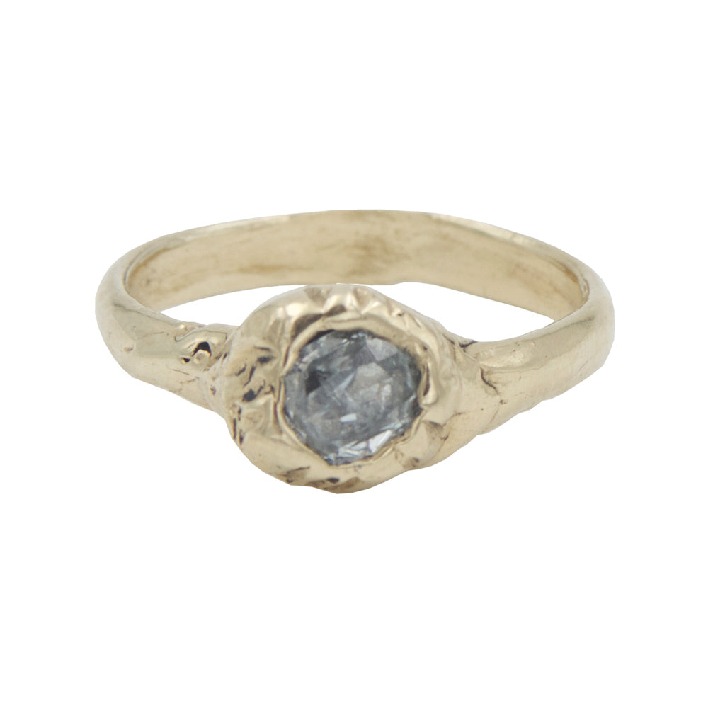 A gold ring with a barnacle detail in the center holding a grey industrial diamond.