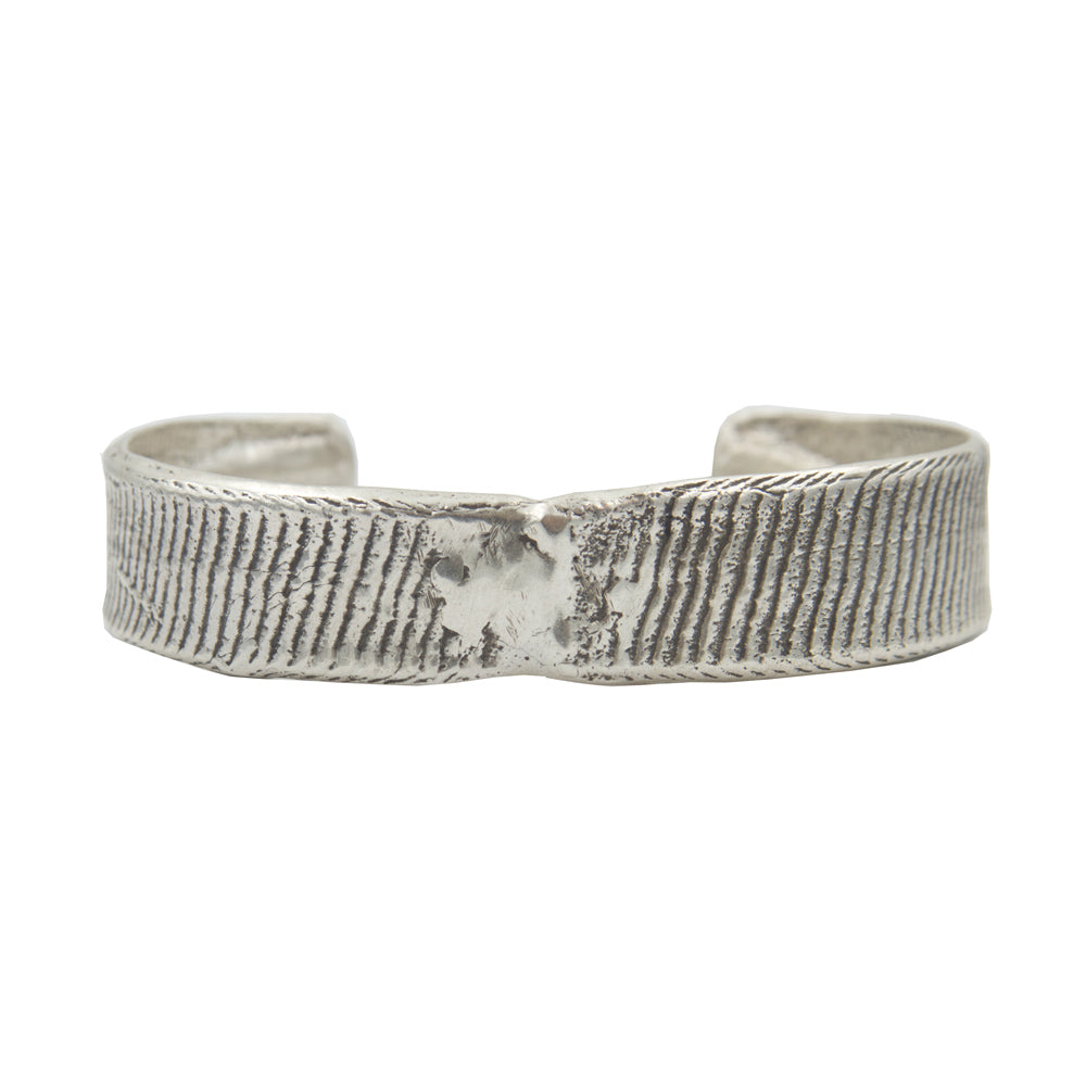 A half inch thick silver cuff bracelet with vertical line details showing texture from cuttlebone.