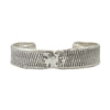 A half inch thick silver cuff bracelet with vertical line details showing texture from cuttlebone.