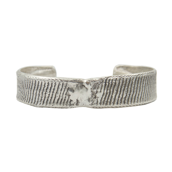 A half inch thick silver cuff bracelet with vertical line details showing texture from cuttlebone.