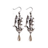 A pair of polished silver earrings in the shape of ships with tear drop shaped pearls hanging from the ships hull.