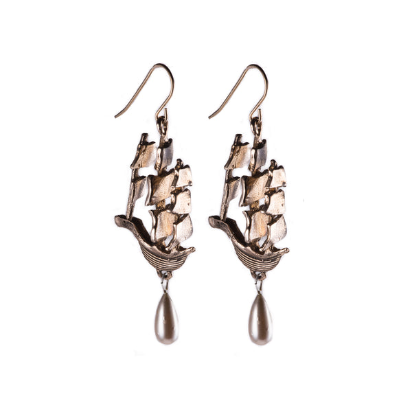 Pair of polished bronze earrings in the shape of ships with teardrop shaped pearl dangles handing from ship bottom.