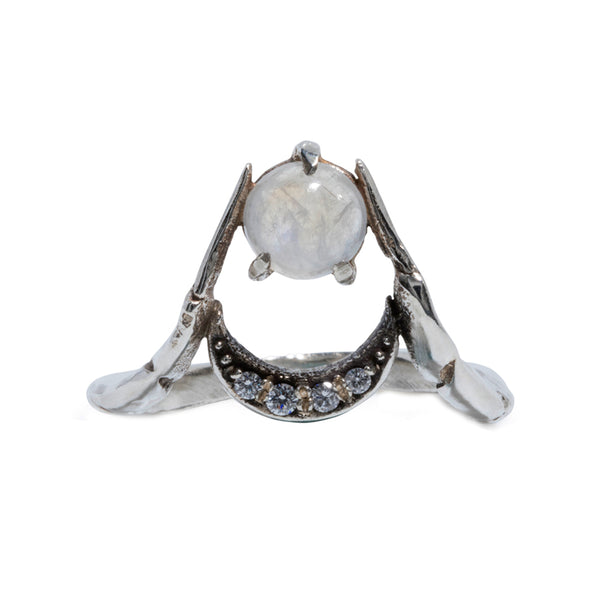 A silver ring of two crab claws holding a crescent moon set with diamonds and a moonstone in the center.