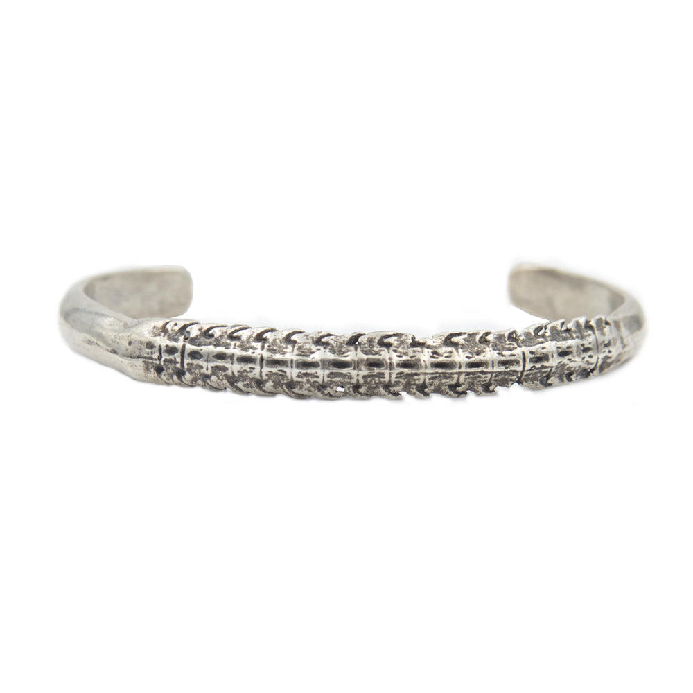 A silver cuff bracelet with a skate spine for the center showing blackened detail.