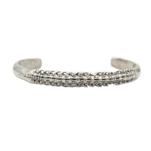 A silver cuff bracelet with a skate spine for the center showing blackened detail.