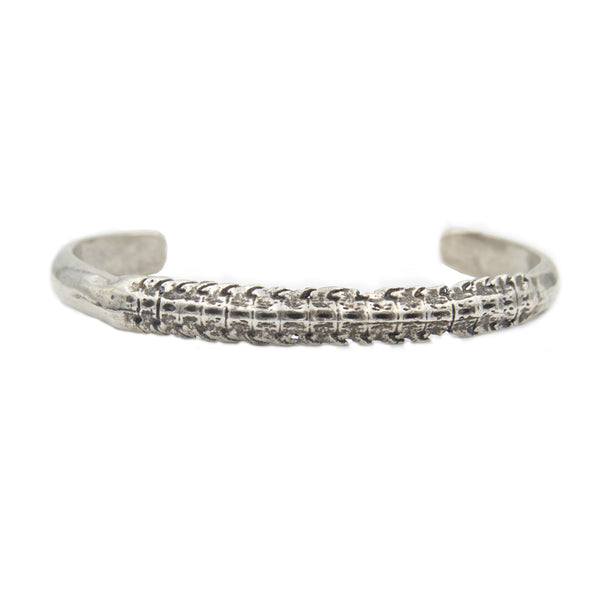 A silver cuff bracelet with a skate spine for the center showing blackened detail.