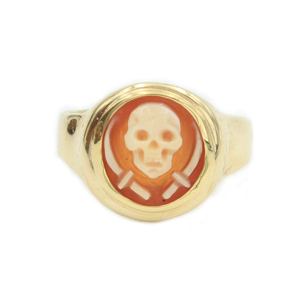 A small gold ring holding 10mm round cameo of a jolly roger symbol or a skull with two swords carved in shell