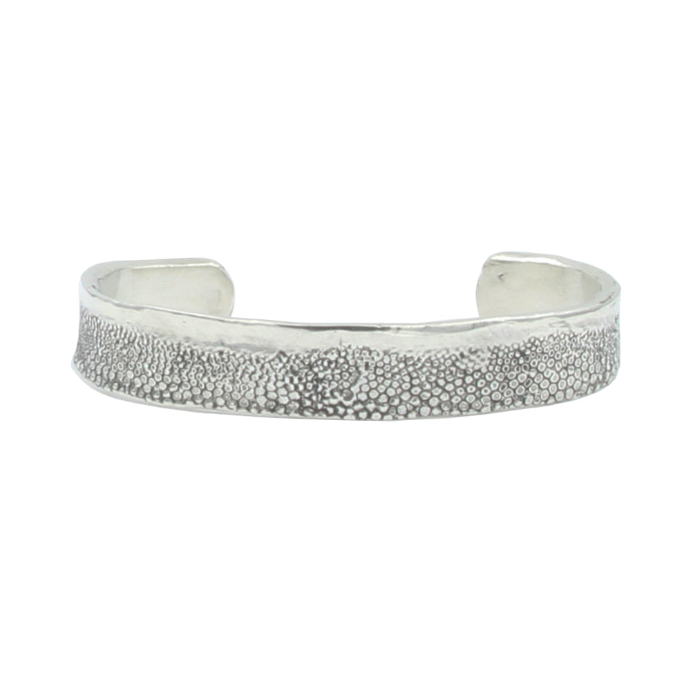 A textured silver cuff bracelet with little circlular details from skate skin.