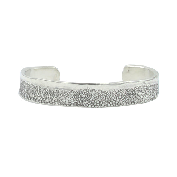 A textured silver cuff bracelet with little circlular details from skate skin.