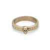 Side view of a gold ring featuring a small skull at the front, with a pattern of circular indentations around the band.