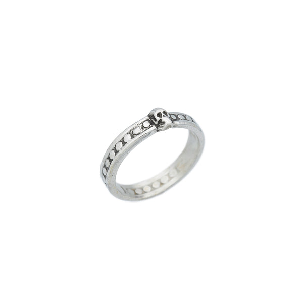 side view of a silver ring featuring a small skull at the front, with a pattern of circular indentations around the band.