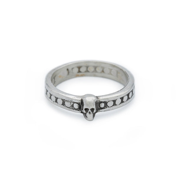 A silver ring featuring a small skull at the front, with a pattern of circular indentations around the band.